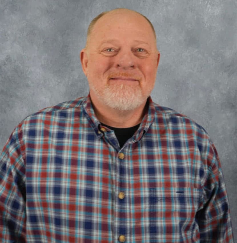 A man with a white goatee smiles