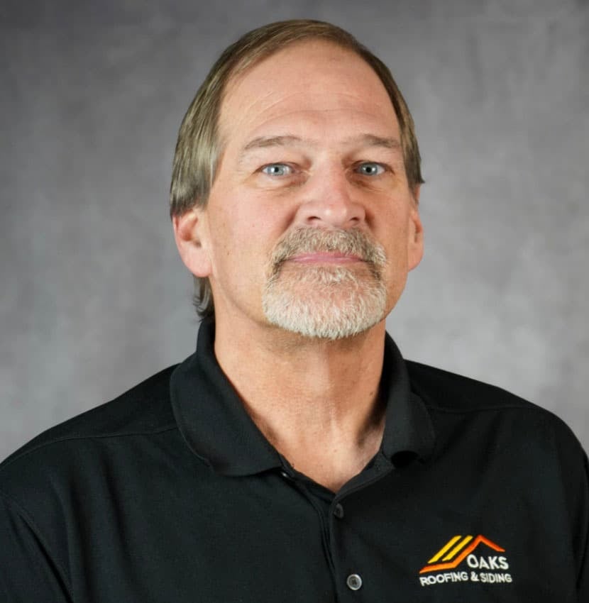 Man with a goatee wearing a black polo shirt with a logo.