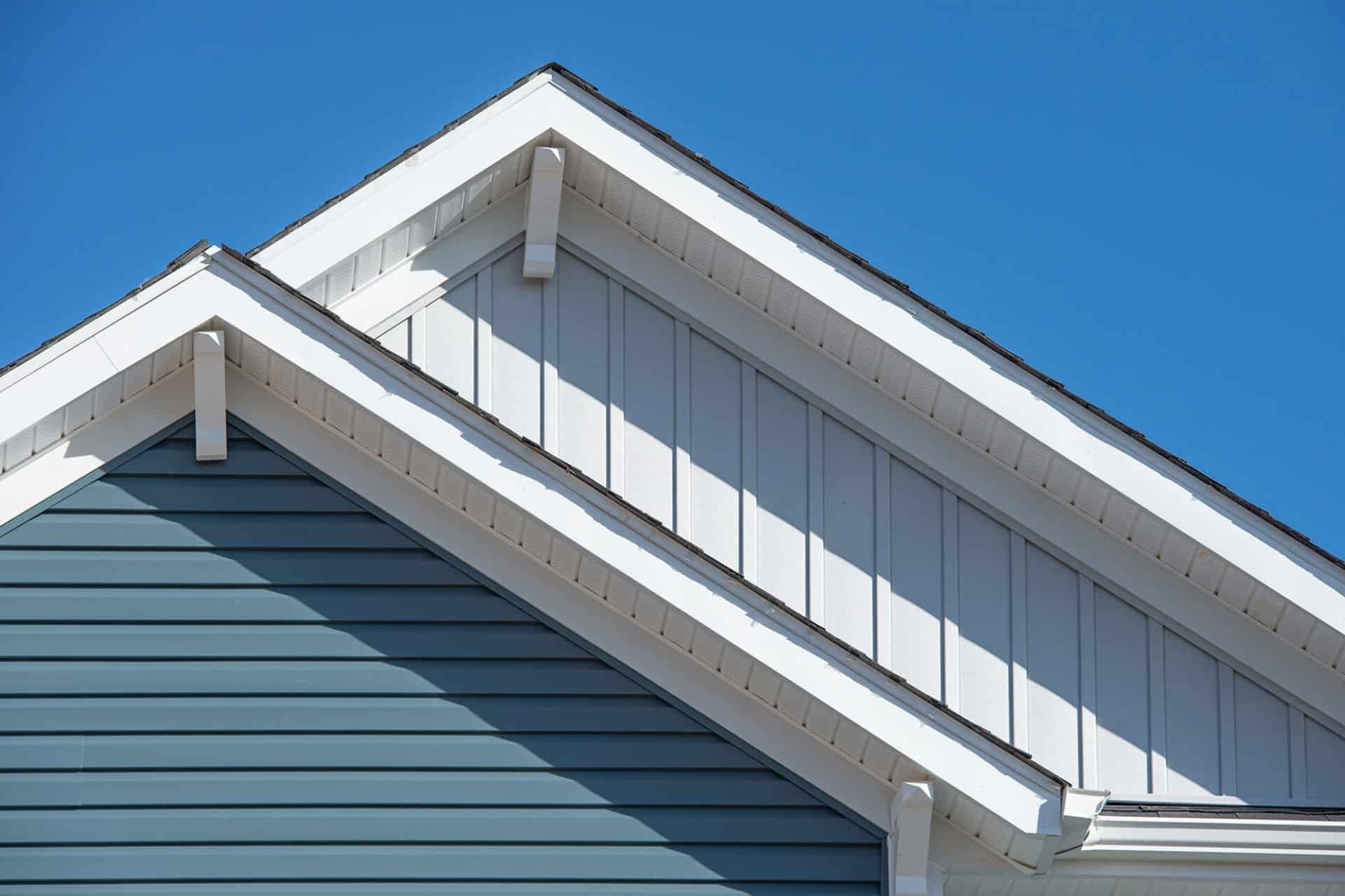 A blue house with white roof edge and soffit. Close-up view.