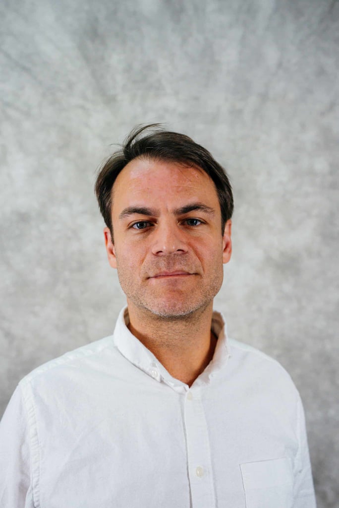 A man with dark hair and a white shirt. He is looking at the camera.