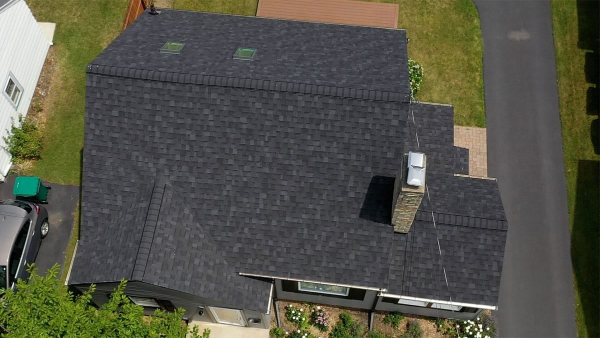 Overhead view of a house with dark shingles and chimney.
