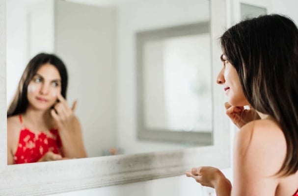 The Best Facial Cleansers for Aging Skin. Attractive woman in her mid thirties practices her skin care routine at home in the bathroom stock photo