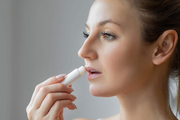 What is a Lip Balm? Woman applying hygienic lip balm on lips stock photo.