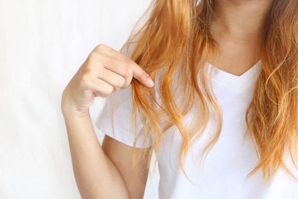 How to Fix Yellow Hair. woman holding her long hairs that with color treatments.