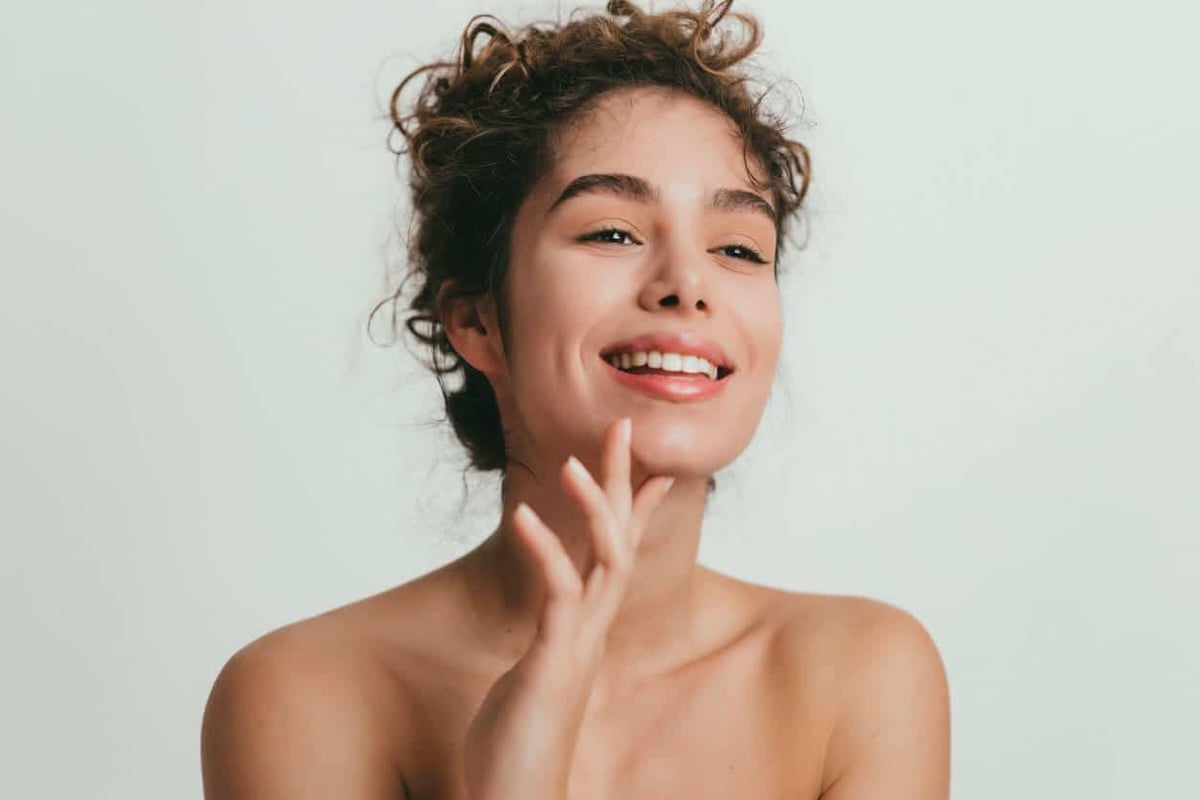The Best Skincare for Oily Skin. Smiling young woman with curly hear and clear skin stock photo.