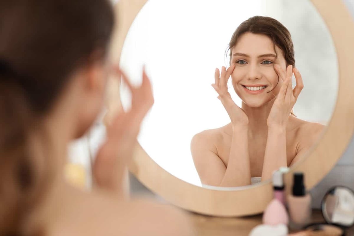 Best IMAGE Skincare Products for Anti-aging. Young woman massaging eye zone, looking at mirror stock photo