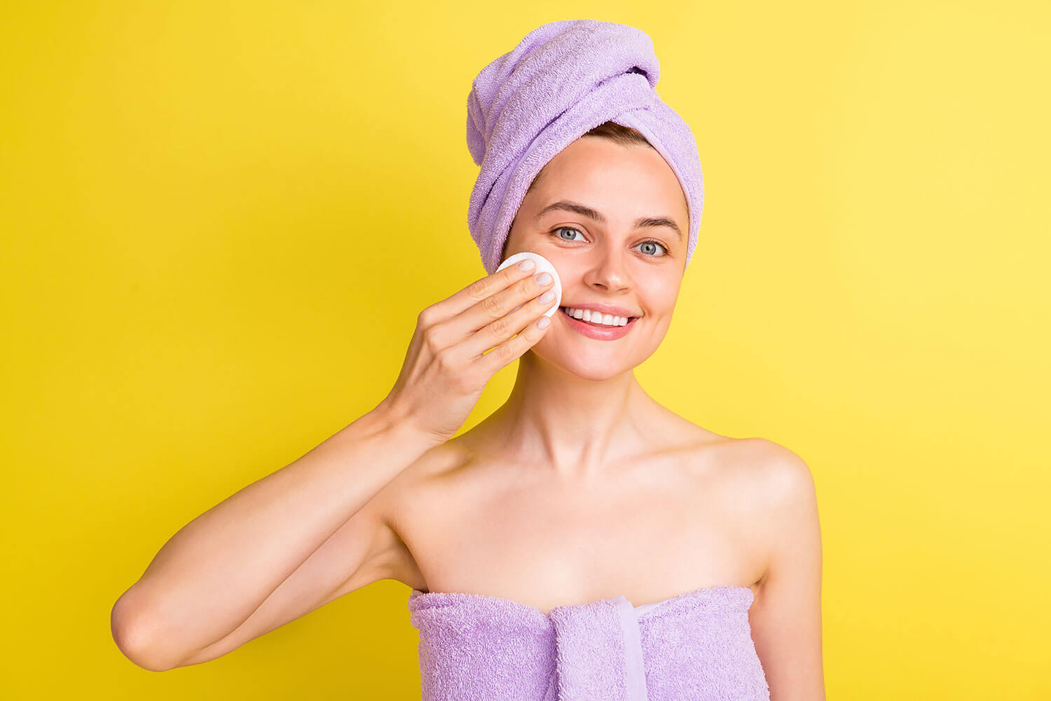 Best Makeup for Oily Skin. Close-up portrait of lovely cheerful girl removing makeup fresh pure skin isolated over bright yellow color background