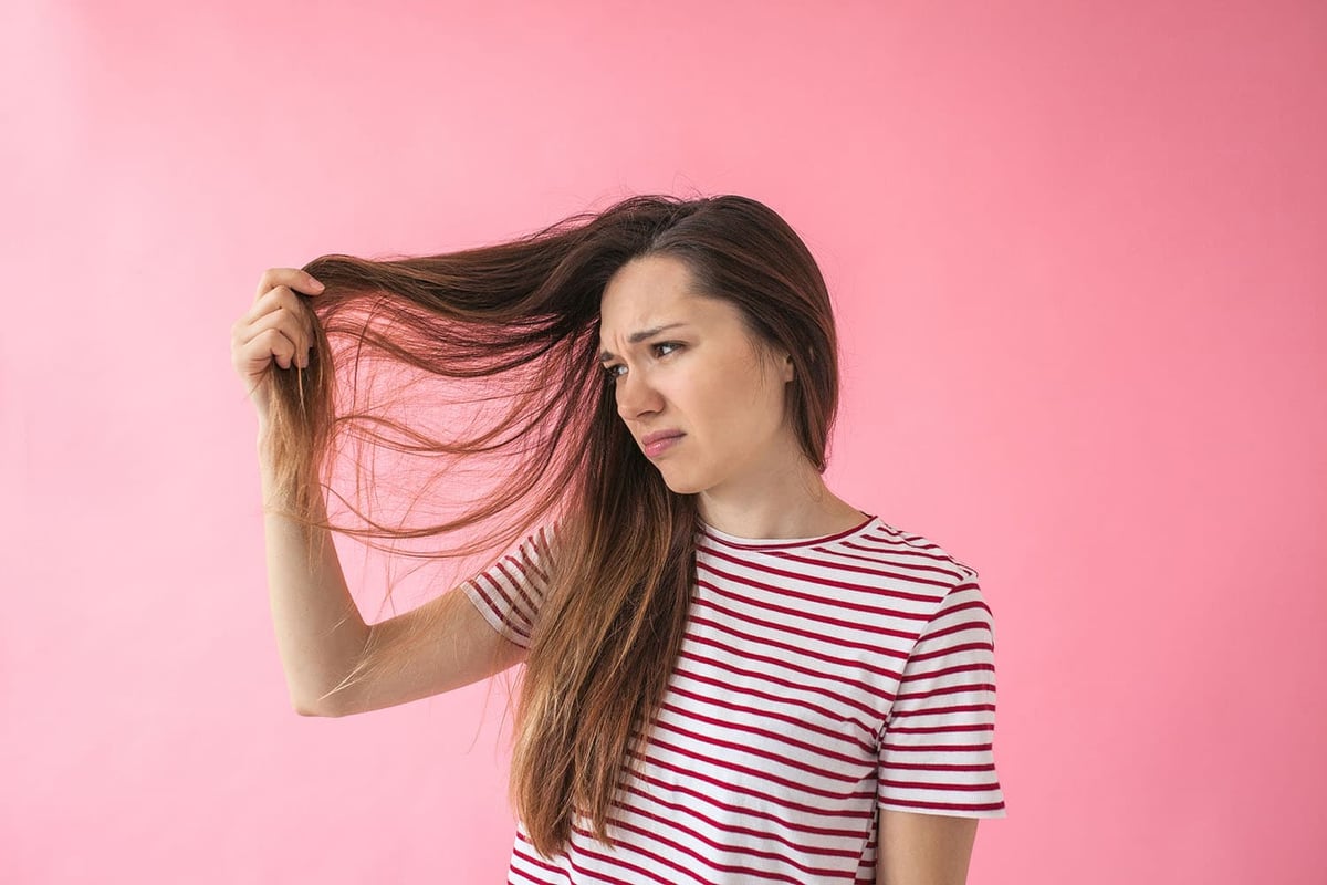 Get Award-Winning Repair with the Best Products for Damaged Hair. The girl is not happy with her hair and shows split ends or dandruff or dry hair or other problems.