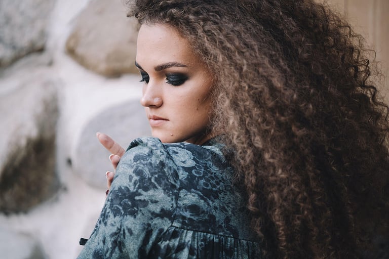 The Best Conditioners for Dry Hair. Photo of woman looking at her shoulder with long curly hair.