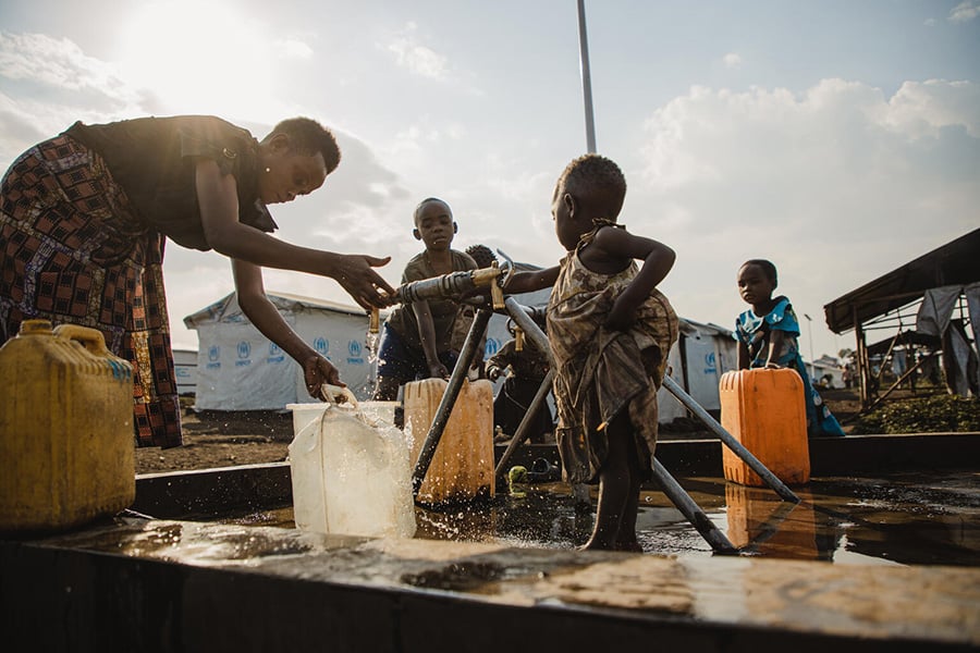 In einem Lager für vertriebene Familien in der Demokratischen Republik Kongo holt eine Mutter Wasser. UNICEF richtet in vielen Flüchtlingslagern Wasserstellen ein, damit Kinder sauberes Trinkwasser haben.
