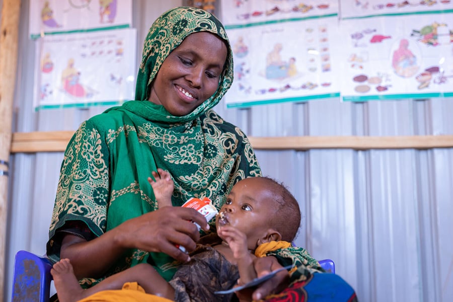 In einem von UNICEF unterstützten Gesundheitszentrum in Äthiopien füttert eine Mutter ihr Kind mit Erdnusspaste. UNICEF versorgt weltweit mangelernährte Kinder mit therapeutischer Nahrung.