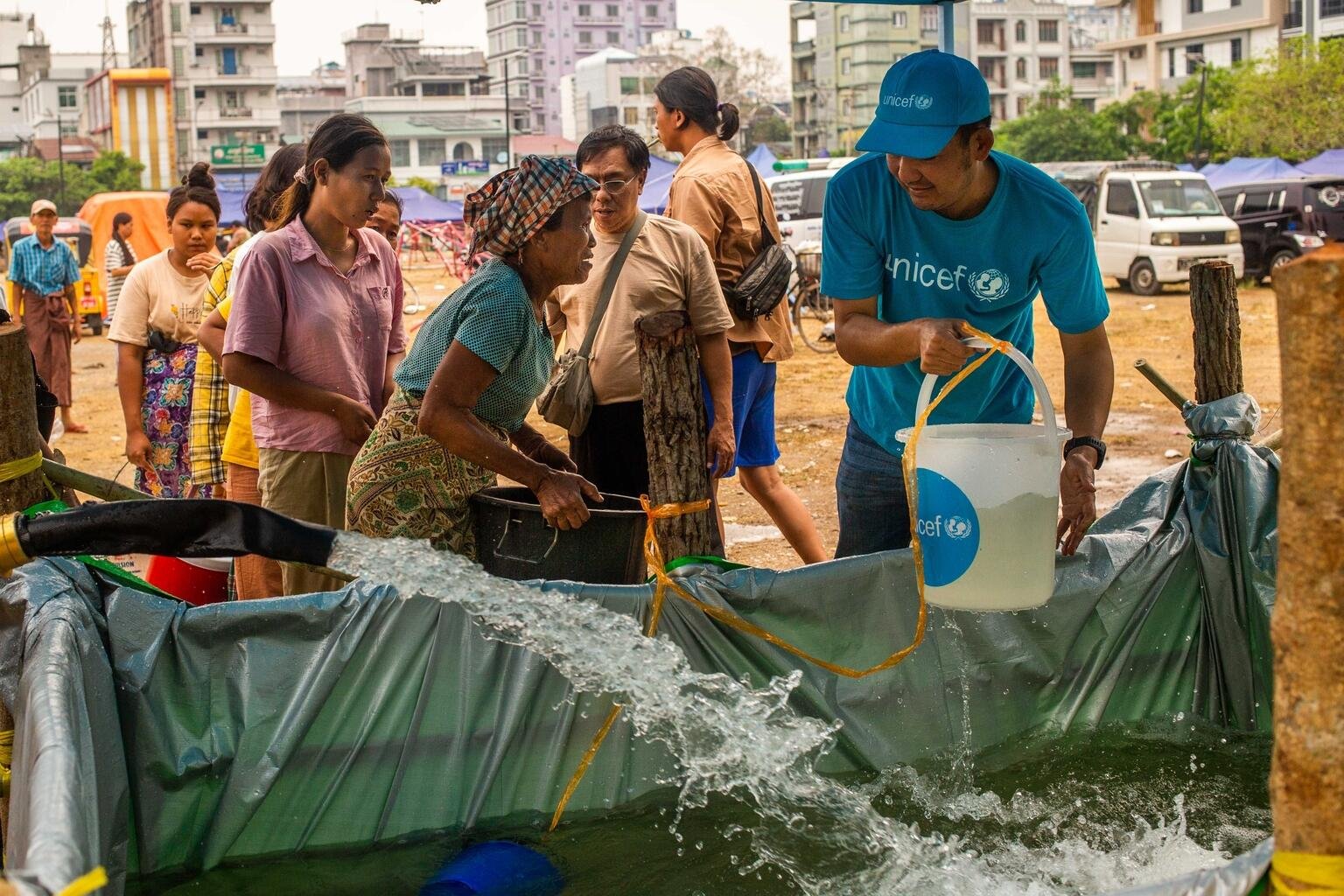 Ein UNICEF-Mitarbeiter verteilt Wasser an Familien in Myanmar.