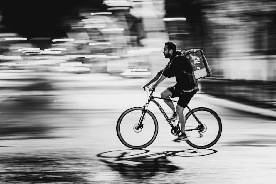 Black and white image capturing a cyclist in motion using panning technique for a dynamic feel.