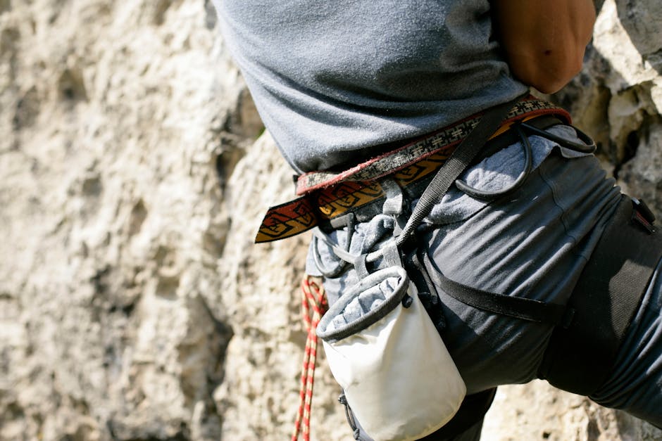 Detailed shot of rock climbing gear including harness and chalk bag during an outdoor climb.