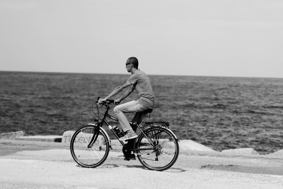 Black and white photo of a cyclist by the sea in Palermo, Italy.