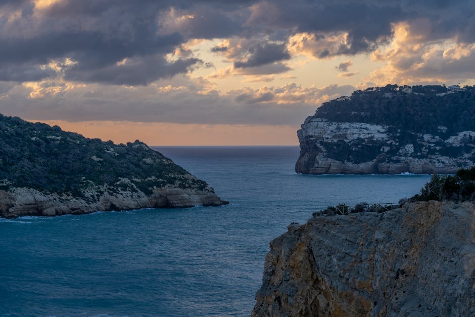 Scenic view of rocky cliffs and tranquil sea in Jávea, Spain at sunset.