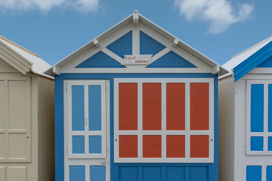 Vibrant blue and red beach hut with 'Les 2 nanas' sign under clear sky.