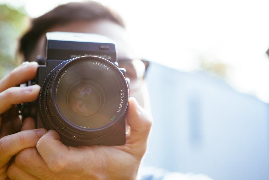 Photographer focusing through a medium format camera lens in natural lighting.