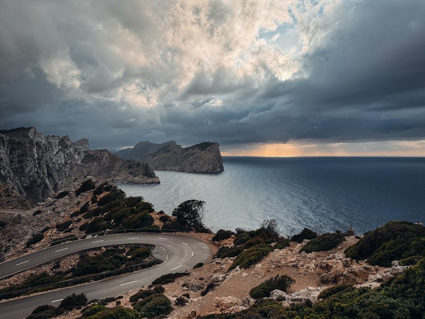 Captivating coastal road view in Mallorca, Spain with dramatic cliffs and sea under a cloudy sky.