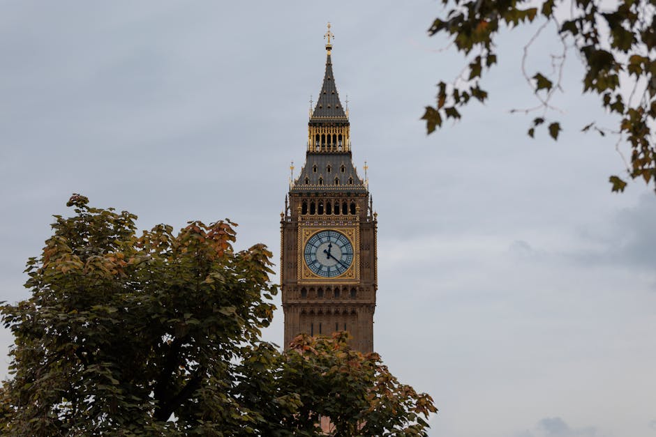 Captivating photo of Big Ben in London framed by autumn trees under a cloudy sky.