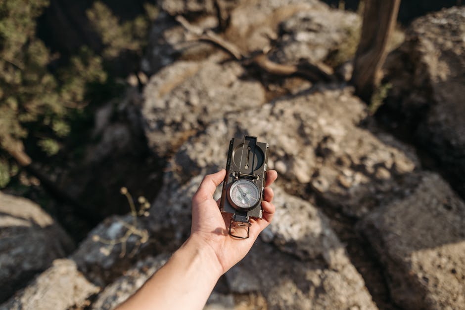 A hand holding a compass over rocky terrain, ideal for navigation themes.