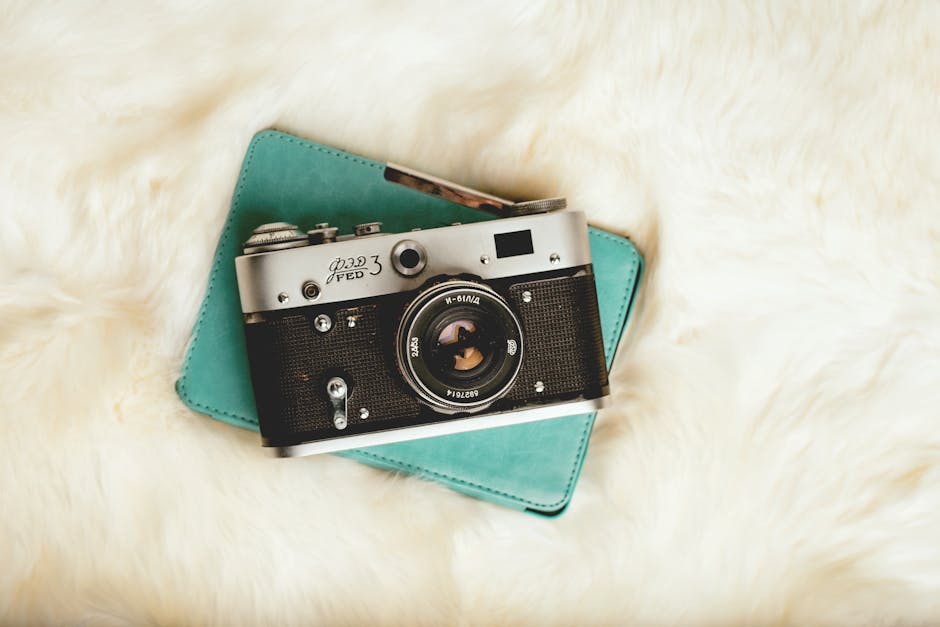 A stylish vintage FED 3 camera resting on a teal notebook atop a plush surface.