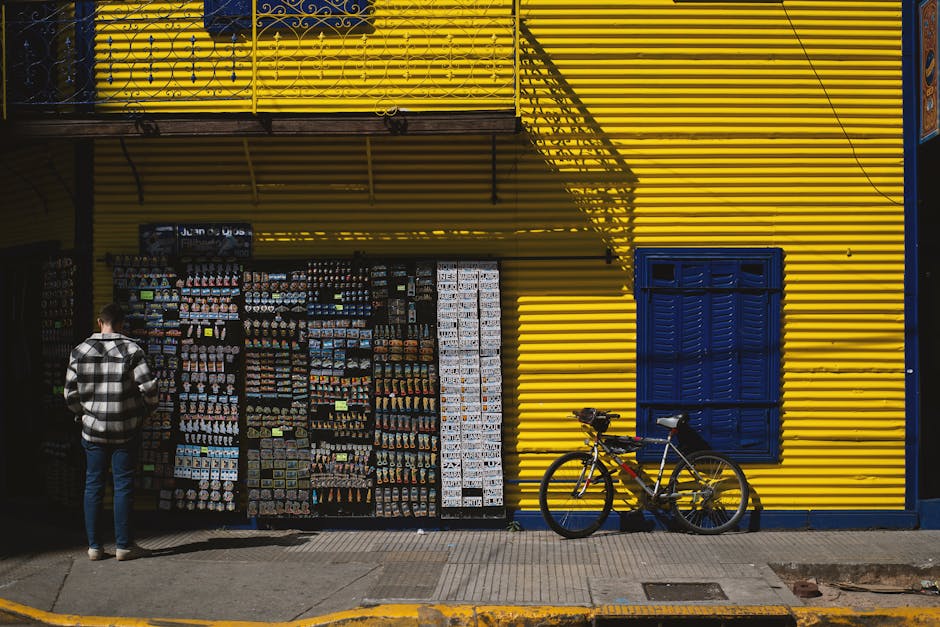 Vibrant yellow and blue facade in La Boca, Buenos Aires featuring a man and a bicycle.