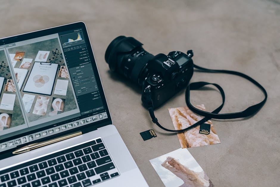 Laptop with editing software alongside DSLR camera and memory cards on a desk.