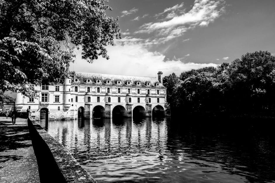 Black and white photo of Château de Chenonceau reflecting over the Cher River in France.