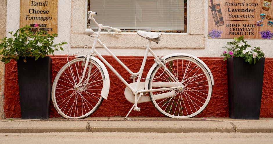 White bicycle against a colorful wall, framed by plants, creating a charming urban street scene.