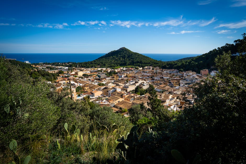 Aerial view of a picturesque Mediterranean town surrounded by hills and sea on a clear day.