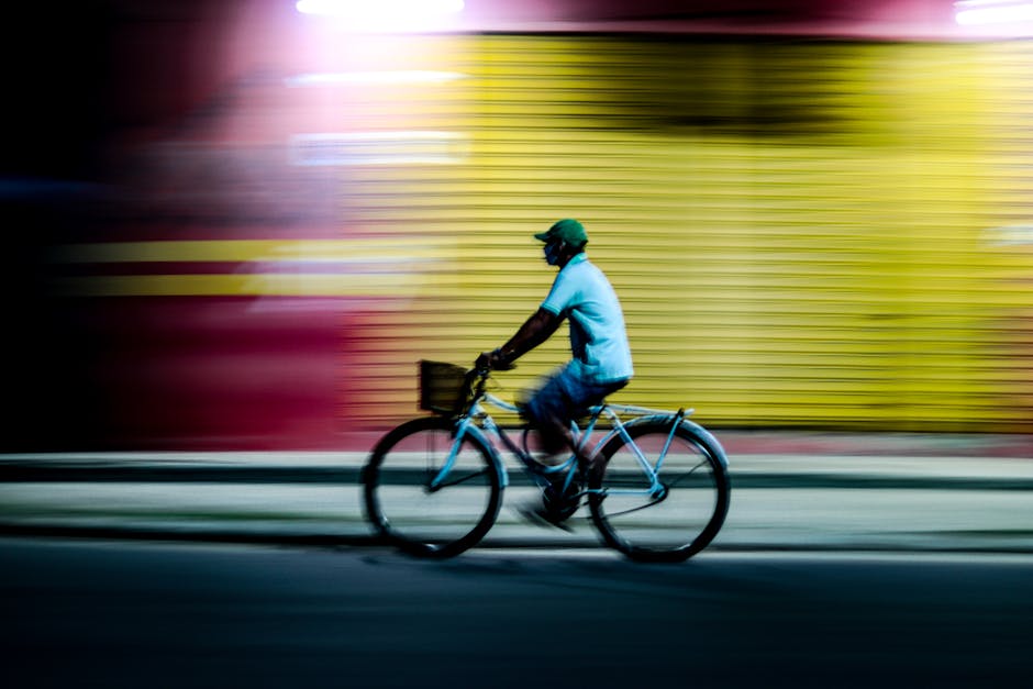 A cyclist rides swiftly past colorful urban scenery at night in Parintins, Brazil. Vibrant, dynamic motion blur captured.