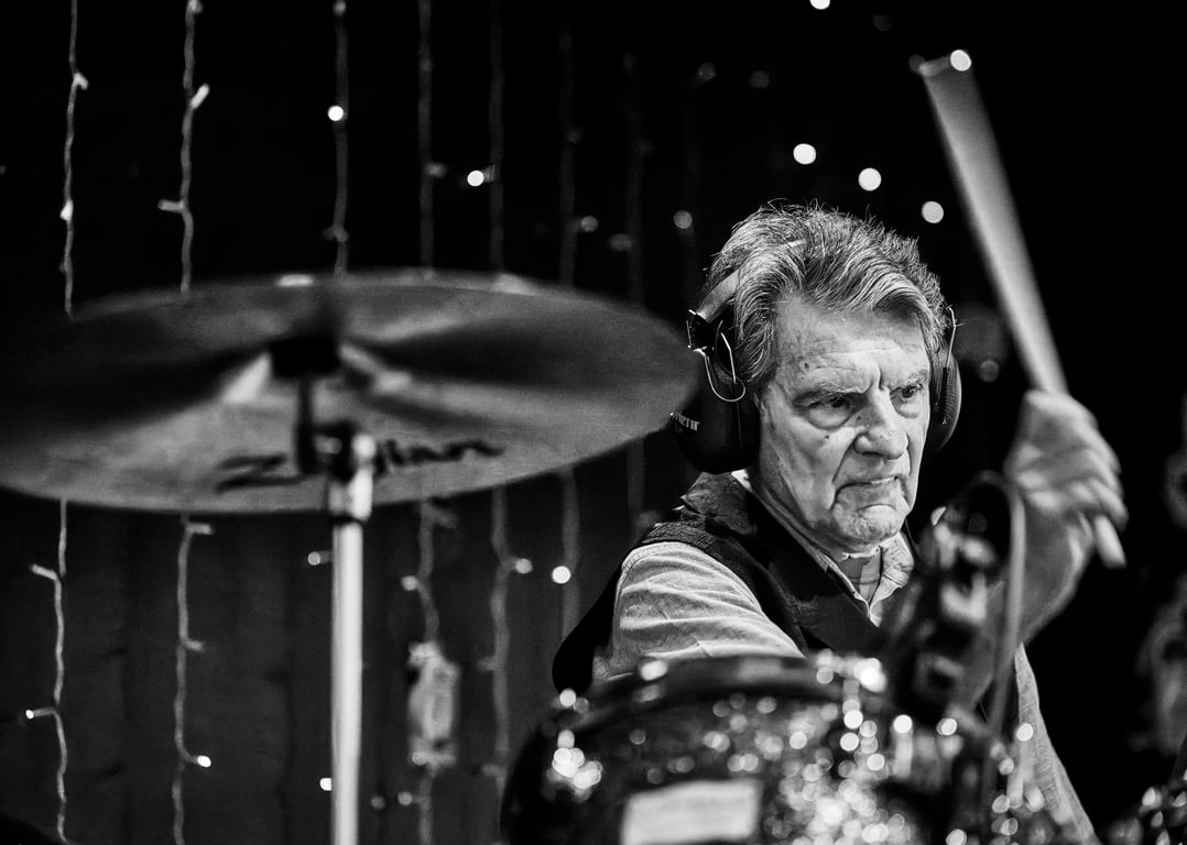 Drummer performing with focused energy on a lit stage