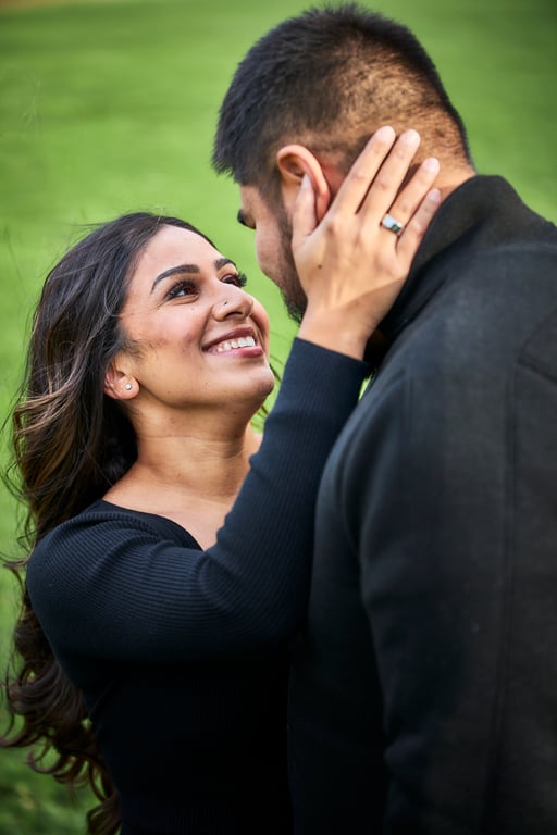 Couple posed together with warm inviting expressions outdoors