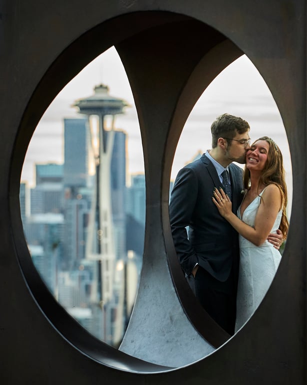 Bride and groom posed with the wedding venue framed behind them