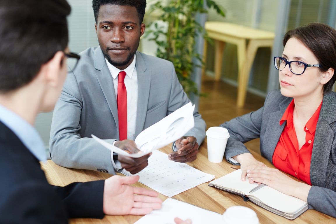 Two colleagues reviewing a contract and discussing terms across the table