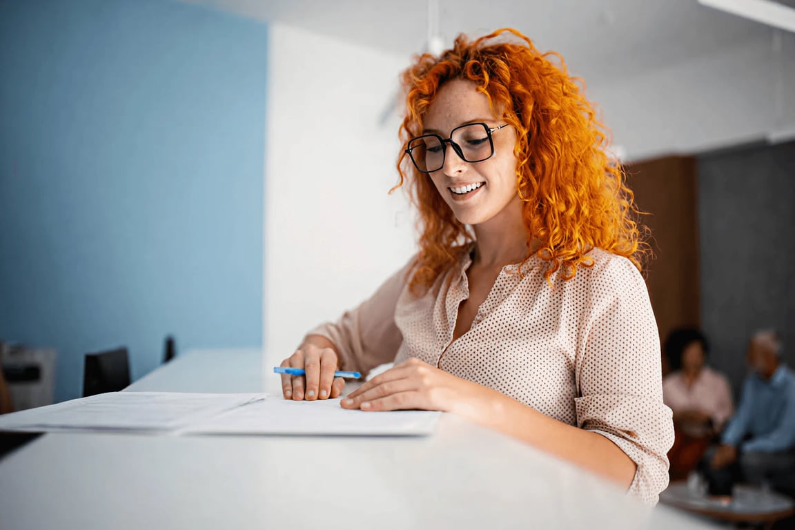 Clinician with glasses writing notes at her desk