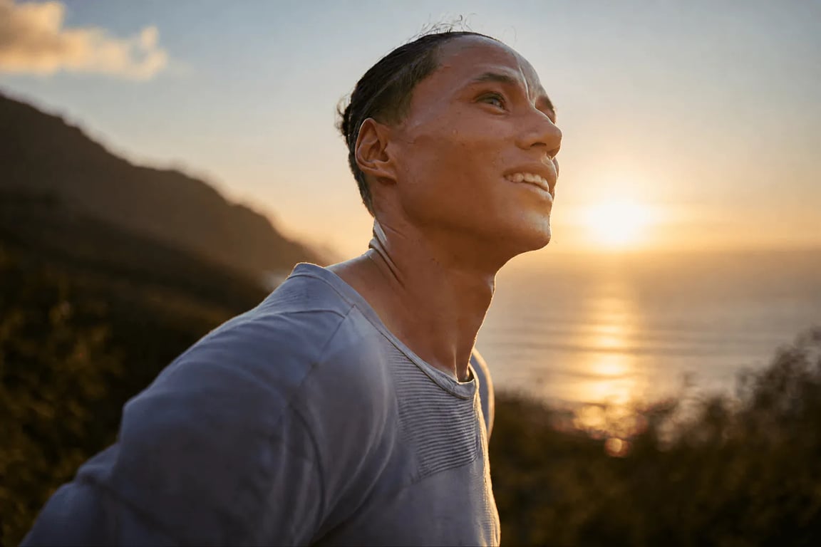 Man smiling toward the sun on a coastal trail