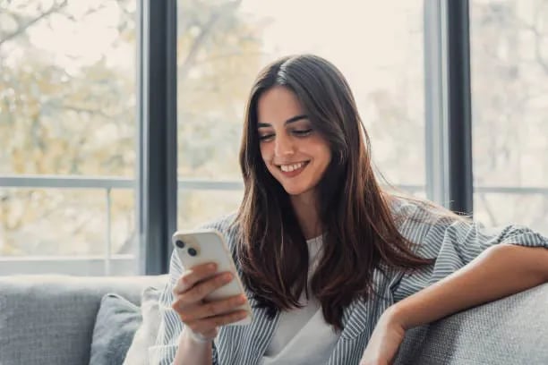 Woman smiling at a reward notification on her phone