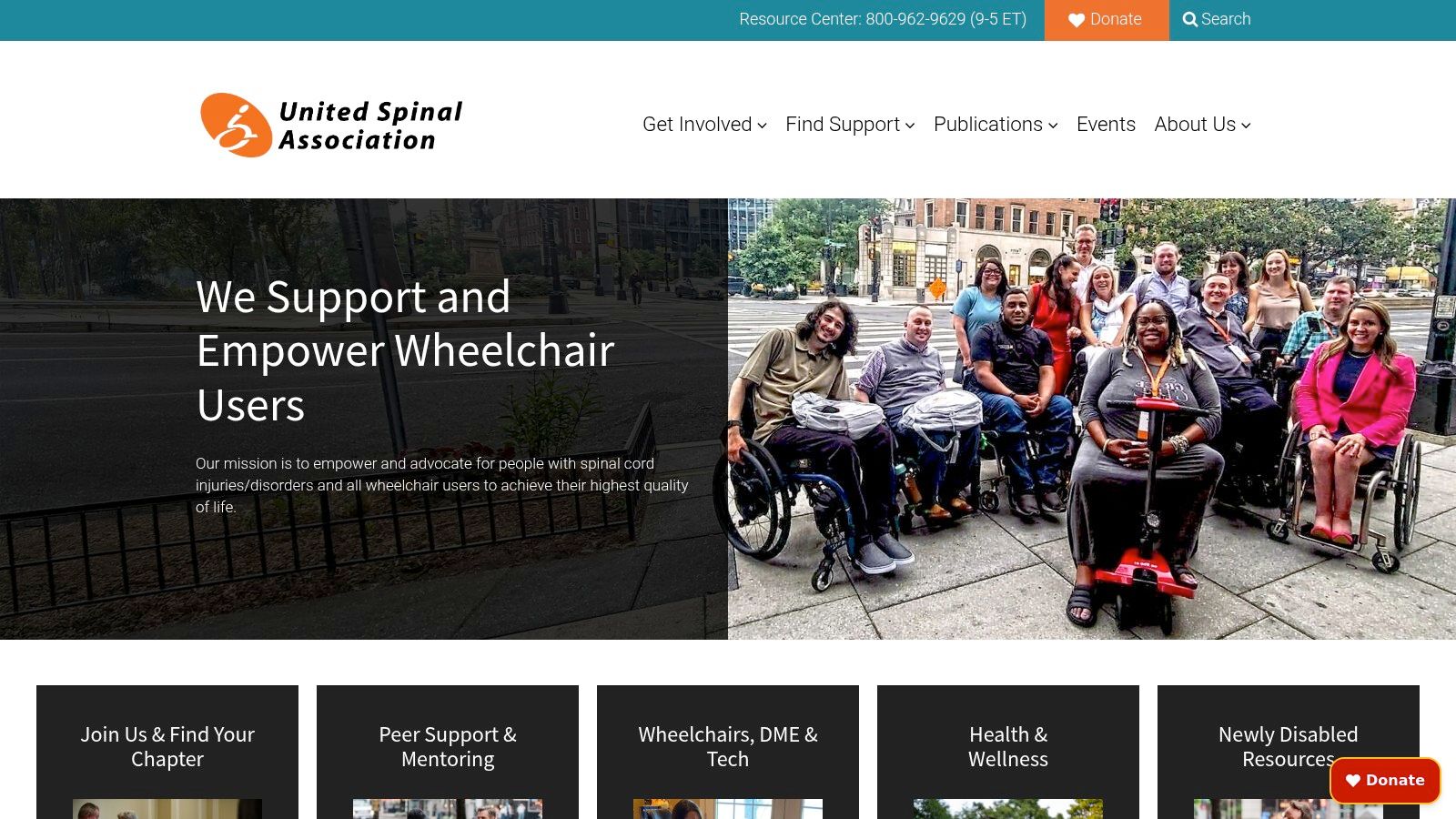 A mentor in a wheelchair smiling and talking with another person, illustrating the peer-to-peer support offered by the United Spinal Association.