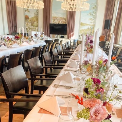 Festlich gedeckte Hochzeitstafel im Löwen-Saal mit leuchtenden Sommerblumen in Glasvasen.