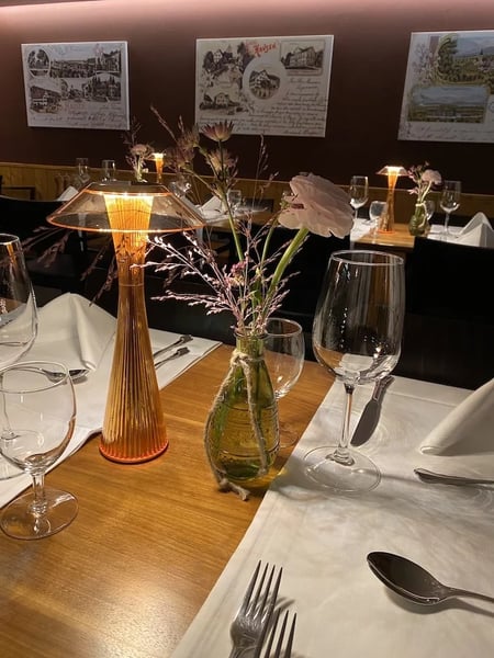 Evening table setting in a traditional 'Stübli' with historic postcards decorating the wood-paneled walls. 