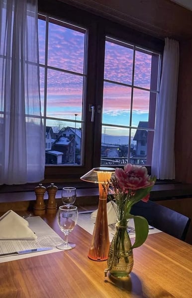 Evening atmosphere in a cozy Stübli with a spectacular pink and purple sunset visible through the window. 