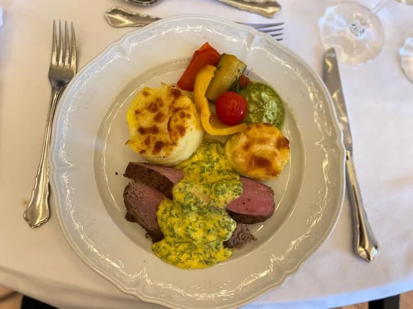 Medium-rare beef fillet with herb butter, served with potato gratin and grilled vegetables.
