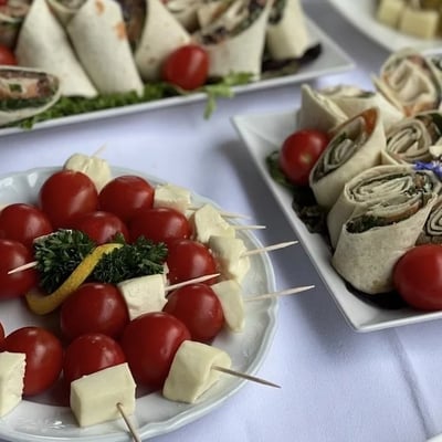 Fresh wraps and tomato-mozzarella skewers, garnished with red currants and herbs. Light summer cuisine in garden setting.