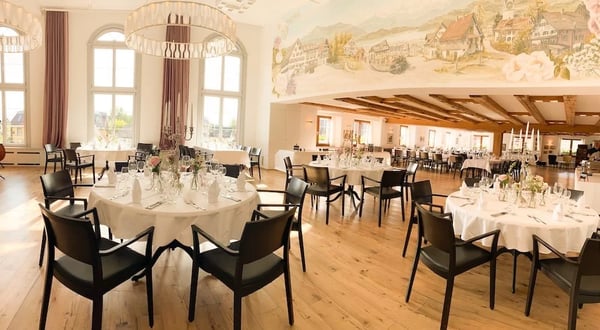 Festively set Löwen Hall with historic style wall painting.