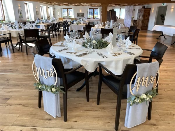 Bridal couple's table with 'Mr & Mrs' chair decorations adorned with white roses and eucalyptus. 
