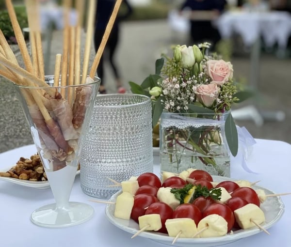 Elegant appetizer with tomato-mozzarella skewers, breadsticks in glass and pale pink roses as table decoration.