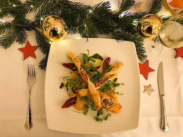 Christmas salmon plate with crispy breadsticks and winter salad. Festively decorated with fir branches and red stars.
