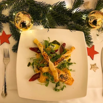 Christmas salmon plate with crispy breadsticks and winter salad. Festively decorated with fir branches and red stars.